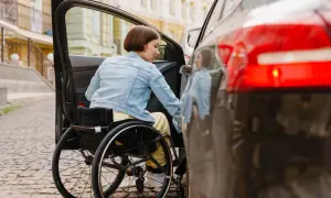 Donna in carrozzina si avvicina all'auto. Scopri lo sconto assicurazione auto legge 104 per una maggiore libertà di movimento.