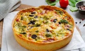 Une délicieuse quiche au poulet, garnie de brocolis, d'olives et de poivrons, prête à être dégustée.