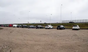 Rząd samochodów na parkingu, w tym czerwony van i białe SUV-y. Zastanawiasz się, ile kosztuje parking na lotnisku w Warszawie?