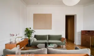 Disposizione divani salotto: un divano verde salvia e uno grigio creano un angolo conversazione accogliente, con un tavolino basso e un mobile vintage.
