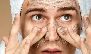 Uomo con scrub viso, pronto per la cura della pelle. Cosa mettere dopo lo scrub viso per un risultato ottimale.