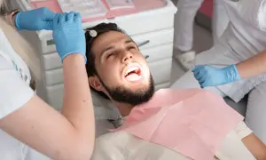 Pacjent u dentysty, który bada zęby. Może to być próchnica pod plombą, która wymaga uwagi.