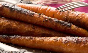 Carottes rôties, caramélisées et légèrement grillées, servies sur une assiette avec une fourchette. Un délice croustillant et savoureux.