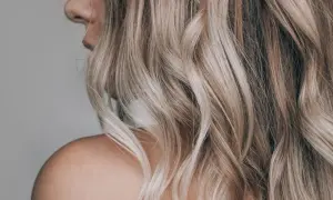 Kobieta z falowanymi, blond włosami w odcieniu sombre. Delikatne przejścia kolorów dodają głębi.