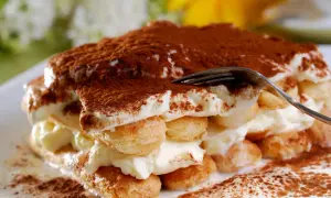 Ein köstliches Tiramisu, die klassische italienische Nachspeise, mit Löffelbiskuits und cremiger Füllung, bestäubt mit Kakao.