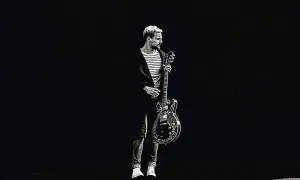 Paweł Domagała z gitarą, jakby gotowy do wykonania utworu "Weź nie pytaj".