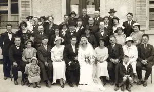 Un groupe de personnes pose pour une photo de mariage. La mariée est au centre, entourée de sa famille et de ses amis. Ce **registre mariage** témoigne d'un jour heureux.