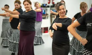 Mujeres aprendiendo como se baila el flamenco, con faldas amplias y movimientos de brazos.