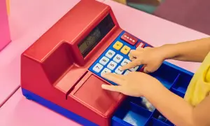 Dziecko bawi się kolorową kasą zabawką, naciskając klawisze.