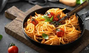 Szybki obiad z makaronem spaghetti w sosie pomidorowym, udekorowany pomidorkami koktajlowymi i bazylią. Idealny na każdy dzień.