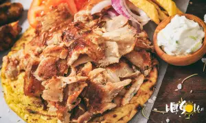 Pyszne jedzenie w Grecji: gyros z kurczaka na chlebku pita, z pomidorami, cebulą, frytkami i sosem tzatziki.