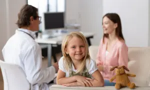Uśmiechnięta dziewczynka z pluszowym pieskiem w gabinecie lekarskim. Czy do dermatologa dziecięcego trzeba mieć skierowanie?