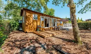 Charmante cabane de pêcheur en bois, avec terrasse, mobilier extérieur et barbecue, nichée dans un cadre verdoyant.