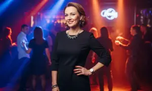 Elegancka kobieta w czarnej sukience, idealna inspiracja, jak się ubrać na dyskotekę po 40. Taniec w blasku świateł.