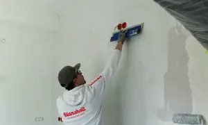 Maler spachtelt Rigips-Wand glatt für ein makelloses Finish.