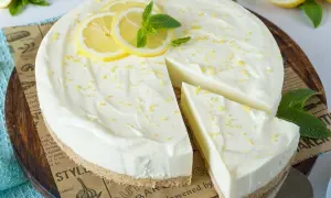 Cremige Philadelphia Torte mit Zitronenscheiben und Minze, ein Stück wurde bereits angeschnitten.
