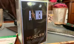 Pudełko perfum Mugler A*Men, zapach dla mężczyzny, w folii, na stole obok szklanki.