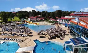 Słoneczny aquapark nad morzem z basenami, zjeżdżalniami i leżakami pod parasolami.