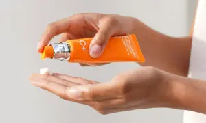 Mani che dosano una crema alla vitamina C sul palmo, per sapere come usare la vitamina c sul viso e ottenere una pelle luminosa.