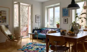 En ljus och färgstark lägenhet med 60-tals inredning. En blå soffa med mönstrat överkast, en trästol med fårskinn och en lekfull matta på parkettgolvet.