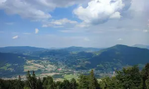 Widok z **szczebel szczyt** na dolinę z polami i lasami. Chmury na błękitnym niebie.