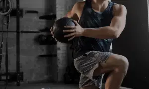 Uomo in palestra esegue un esercizio con palla medica. Gli aminoacidi essenziali a cosa servono? Aiutano la costruzione muscolare.