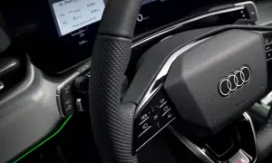 Wnętrze nowoczesnego samochodu Audi. Kierownica z przyciskami, ekran z informacjami o podróży i zielone podświetlenie. Czy to elektryczny samochód?