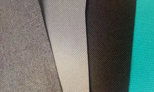Sztuczny materiał kodura w odcieniach szarości, czerni i turkusu. Widoczne drobne, regularne wzory.