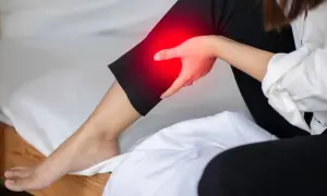 A person holds their leg, which is highlighted in red, indicating pain. This image explores the question: can a bad mattress cause leg pain?