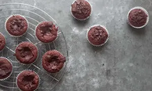 Pyszne babeczki brownie, udekorowane kawałkami czekolady, stygną na kratce.