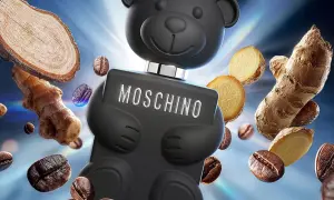 Czarny flakon Moschino Toy Boy w kształcie misia otoczony ziarnami kawy i imbirem.