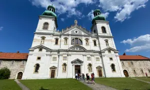 Majestatyczny klasztor Ojców Kamedułów na Bielanach z zielonymi kopułami wież, pod błękitnym niebem z chmurami.