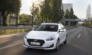 Biały Hyundai i30 1.6 benzyna jedzie autostradą w słoneczny dzień.