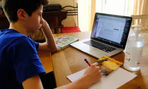 Chłopiec uczy się zdalnie, przed nim laptop, podręczniki i notatnik. Mam nadzieję, że jego **oceny** będą dobre.