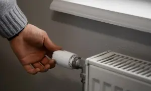 Dłoń reguluje zawór grzejnika, pokazując, jak zakręcić grzejnik bez termostatu.