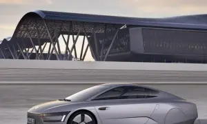 Srebrny, futurystyczny vw xl1 z charakterystycznym dachem i nowoczesnym budynkiem w tle.