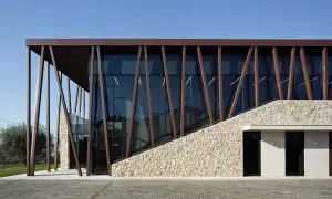 Edificio moderno con facciata in pietra e vetro, travi inclinate in metallo marrone. Un'architettura che evoca i valetti di Bardolino.