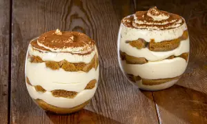 Due bicchieri di delizioso tiramisù senza uova, stratificato con crema e savoiardi, spolverato di cacao.