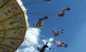 Flugkarussell auf dem Volksfest Gmund. Menschen schweben im Himmel, die bunte Kirmes dreht sich.