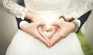 Dla mojej siostry, najpiękniejsze życzenia na ślub! Dłonie tworzą serce na tle białej sukni.