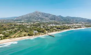 Widok na marbella beach z turkusową wodą, piaszczystą plażą i górami w tle.
