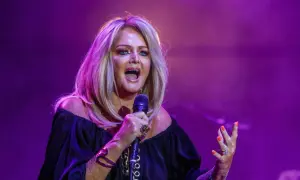 Eine Frau mit blonden Haaren singt leidenschaftlich ins Mikrofon, als würde sie ihre liebsten Karaoke-Songs performen.
