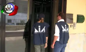 Agenti della DIA, Direzione Investigativa Antimafia, si avvicinano a un ingresso.