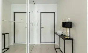 Nowoczesny wiatrołap inspiracje: białe drzwi, lustrzana szafa i elegancka konsola z lampą.