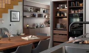 Comedor y zona desayuno cocina con mesa de madera, sillas grises y estanterías empotradas.