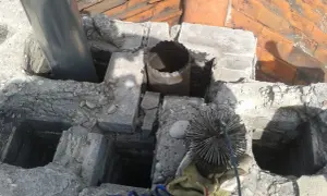 Rozbiórka komina w domu. Widoczna szczotka kominiarska, rura i fragmenty dachu.