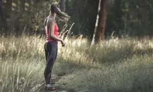 Frau im Laufoutfit im Wald. Sie genießt die Natur und die Ruhe, die das Joggen mit sich bringt.