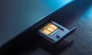 Złota karta SIM w wysuwanej tacce telefonu. Numer karty SIM jest kluczem do łączności.