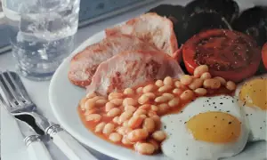 Pyszne jedzenie w Wielkiej Brytanii: fasolka, jajka sadzone, pomidor, boczek i pieczarki. Idealne na prezentację!