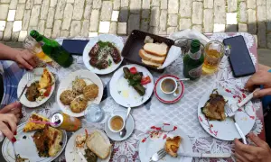 Pyszne albania jedzenie: mięso, gołąbki, placki i pieczywo na stole, obok piwo i kawa.